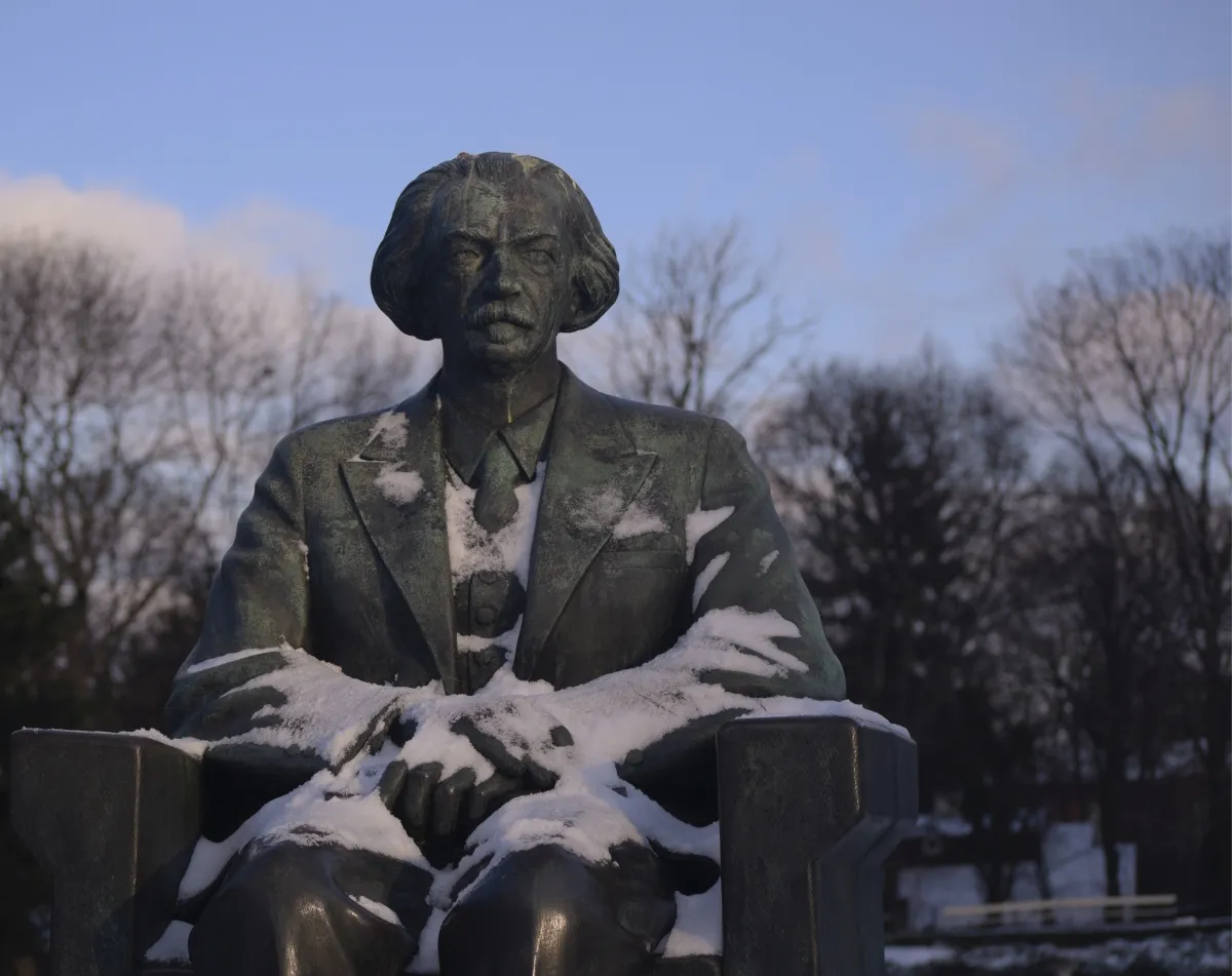 Bronze seated bust dusted with snow in a park
